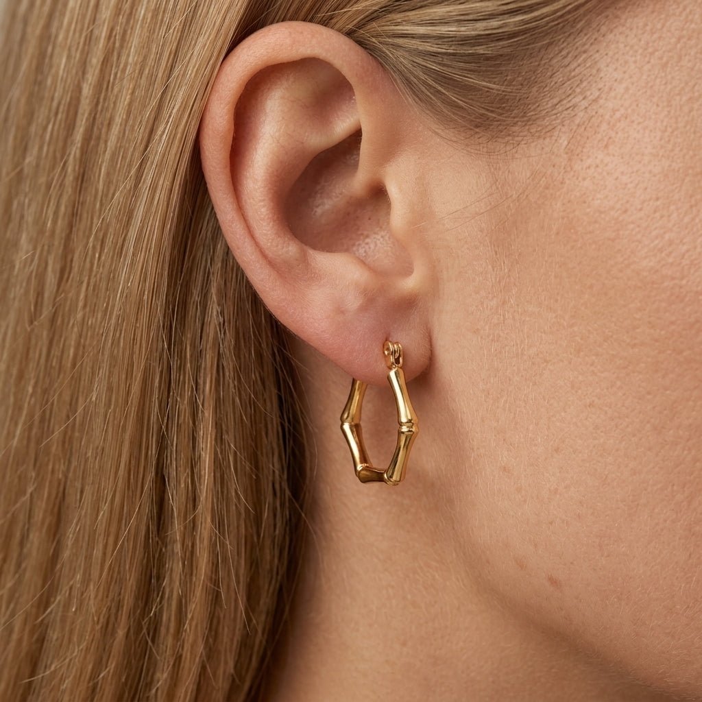 bamboo earrings, gold bamboo hoop earrings worn on ear with geometric bamboo inspired design, lightweight statement jewelry with a sleek tropical vintage feel
