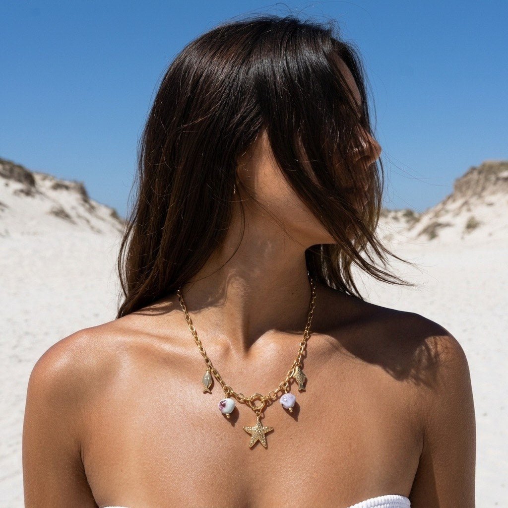 beach charm gold necklace with starfish, fish and shell details styled by the ocean