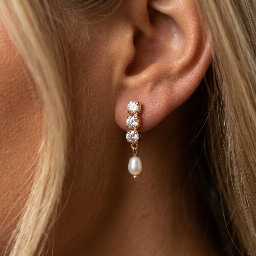 cubic zirconia drop earrings gold drop earrings with round cubic zirconia stones and pearl charm worn on ear elegant jewelry