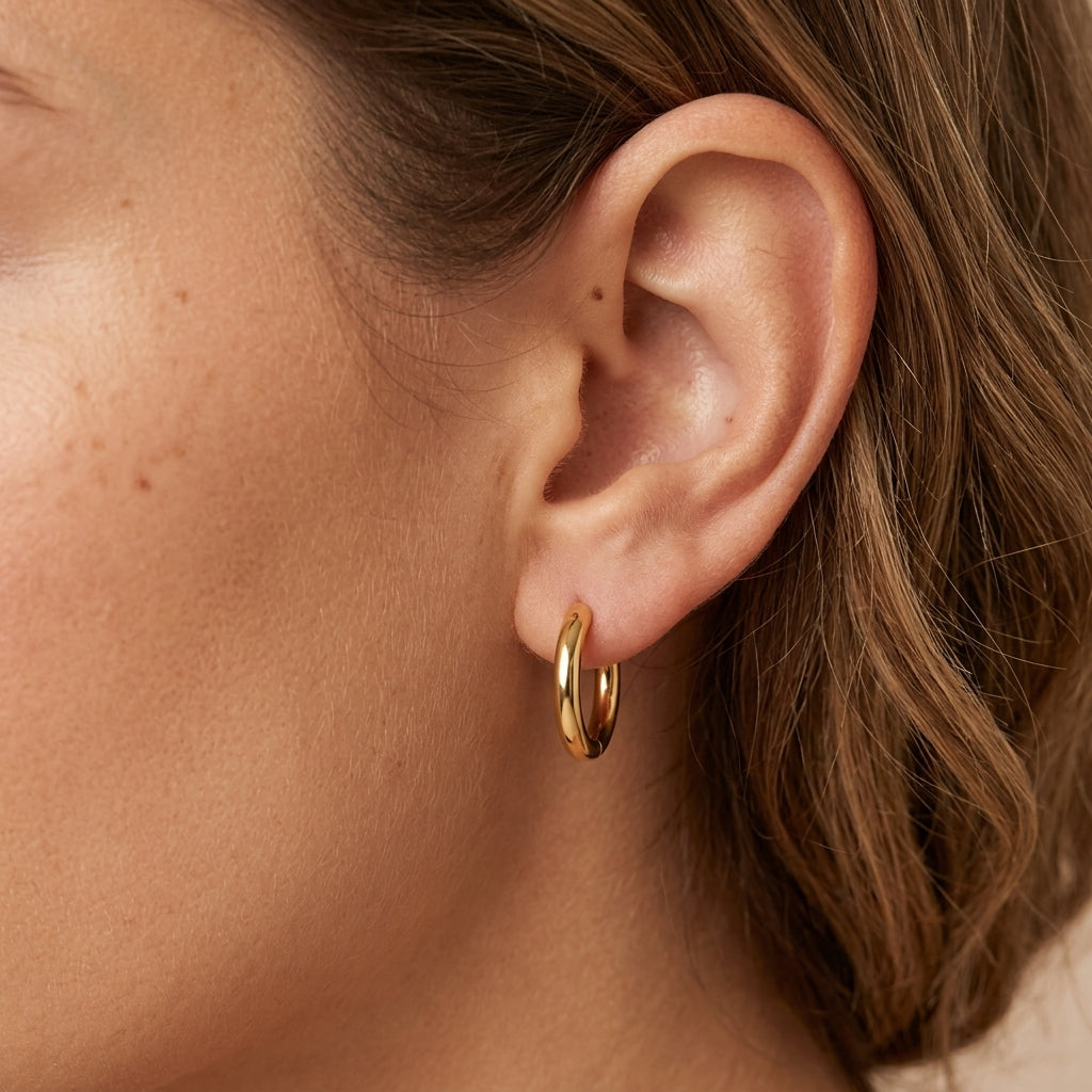 everyday gold hoop earrings featuring a medium sized polished gold design styled on a model for a chic and timeless jewelry look