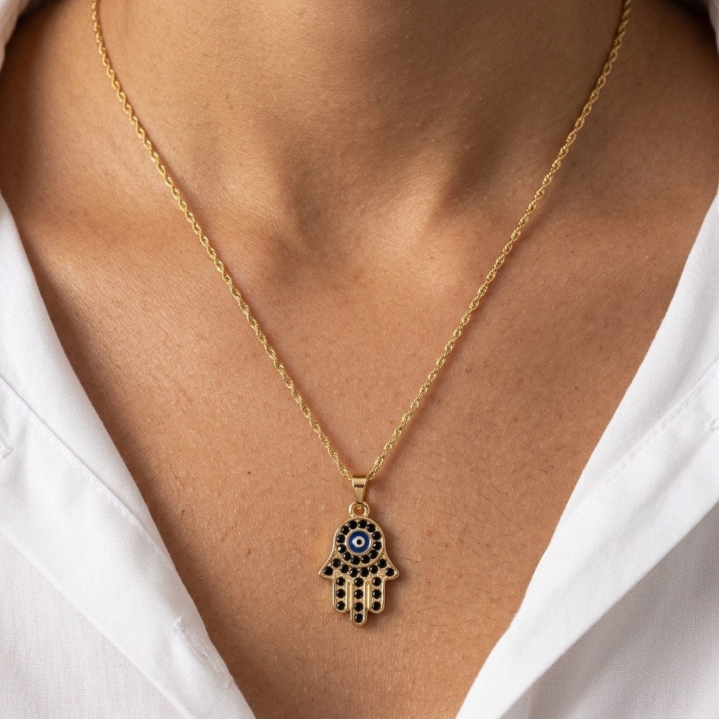 evil eye hamsa necklace featuring a blue eye motif and sparkling black stone accents