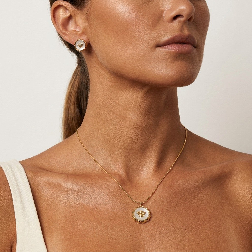 gold bee pendant necklace featuring a white medallion and detailed bee charm