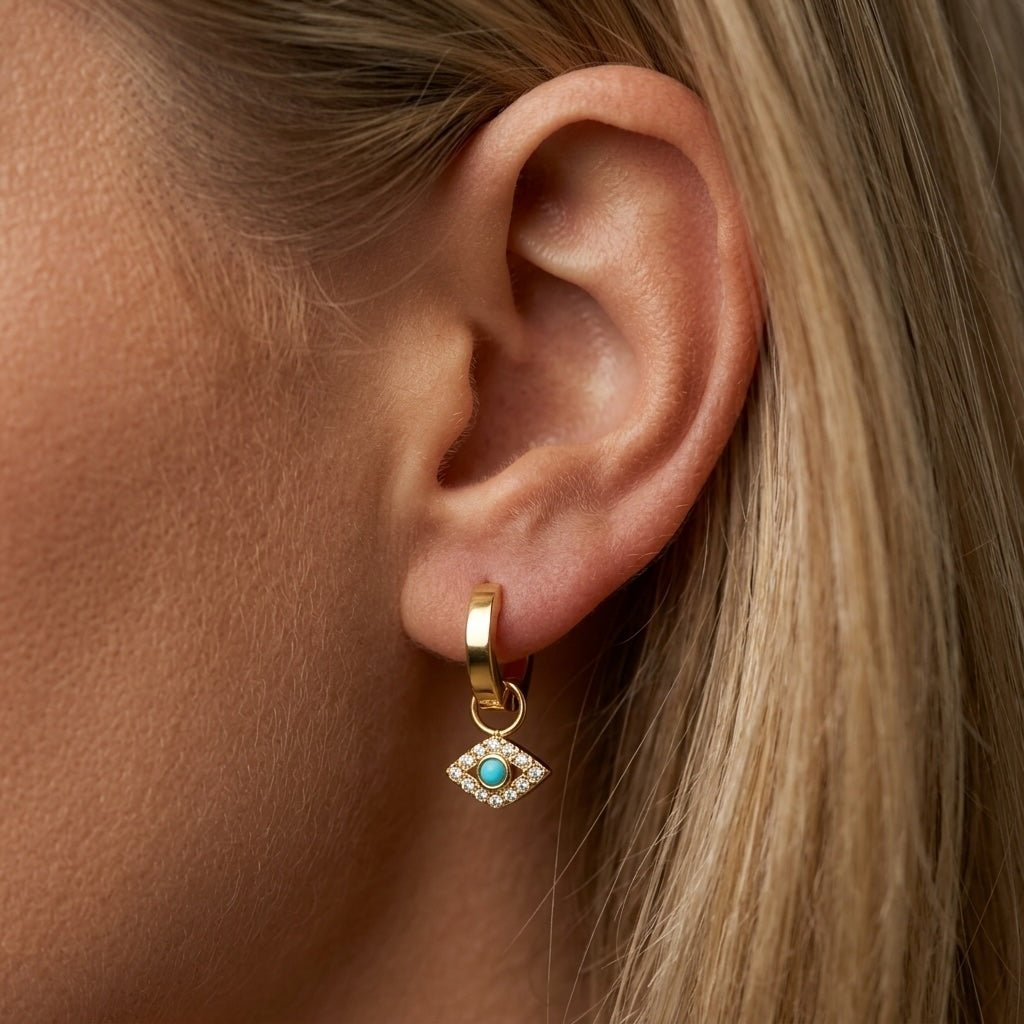 gold evil eye earrings gold huggie earrings with a turquoise evil eye charm and crystal details for a protective boho jewelry look