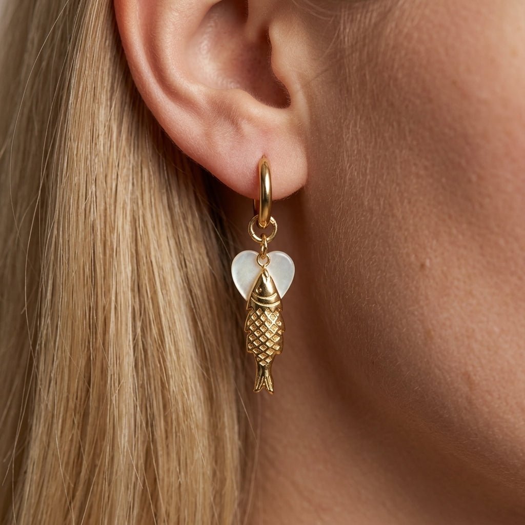 golden fish earrings playful gold fish drop earrings with a textured charm and soft white heart accent on a delicate mini hoop
