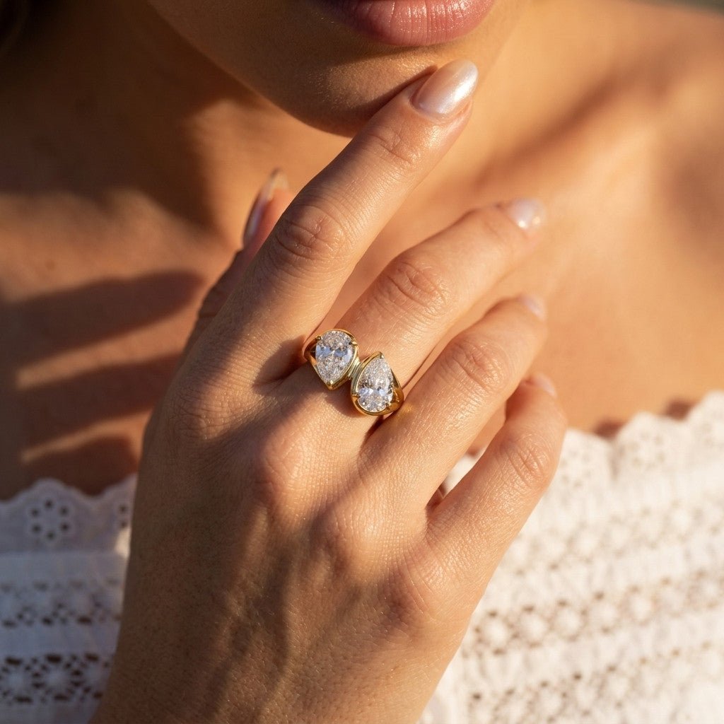 pear cut gold ring with two sparkling clear stones in a modern open band