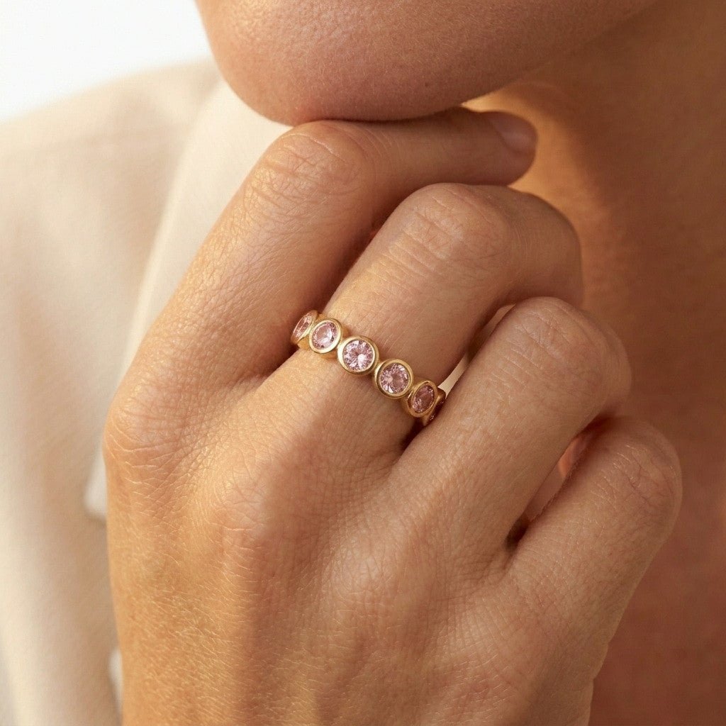 pink stone gold ring with sparkling round stones in a polished gold setting