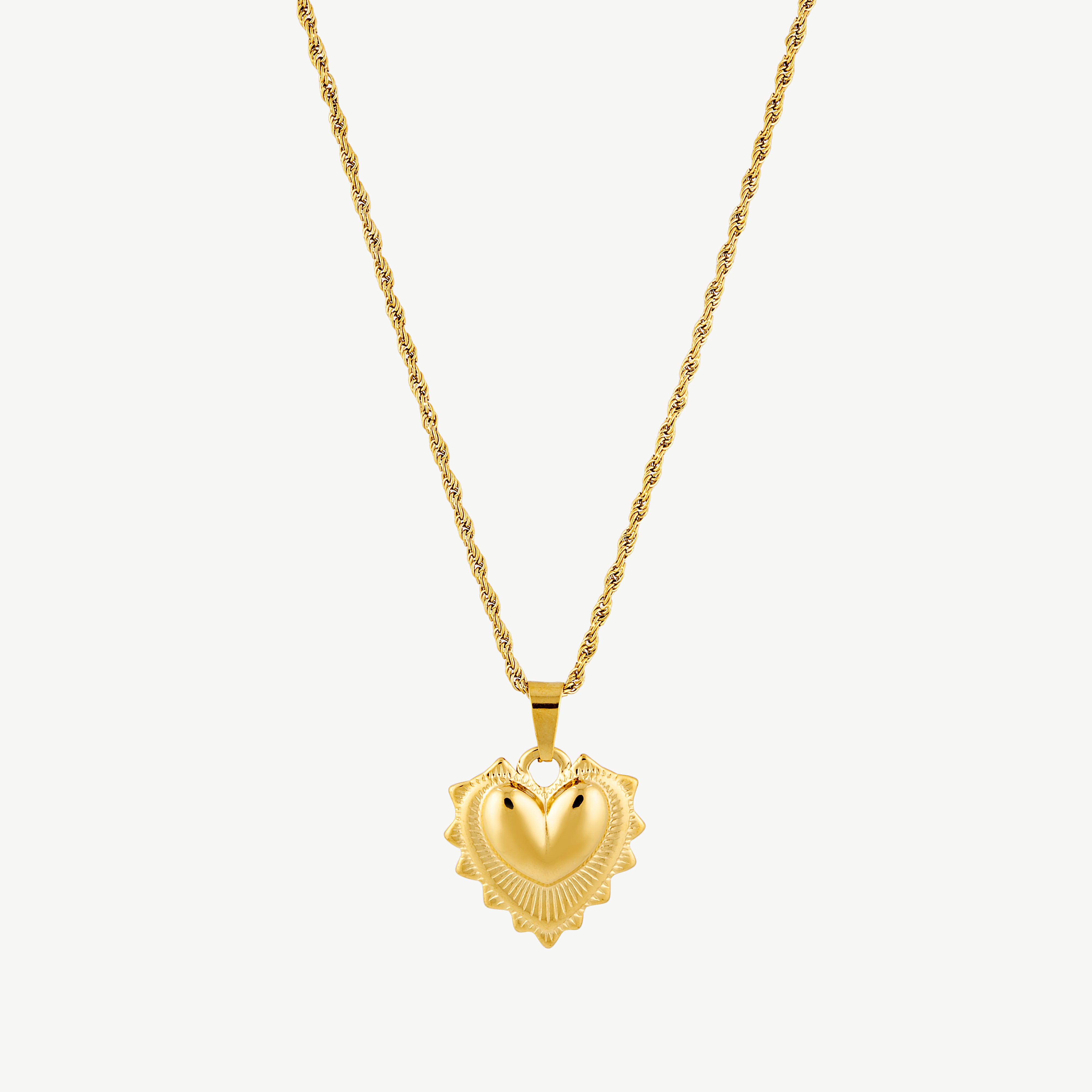 puffy heart necklace with sculptural gold heart pendant framed by detailed edging and suspended from a textured gold chain