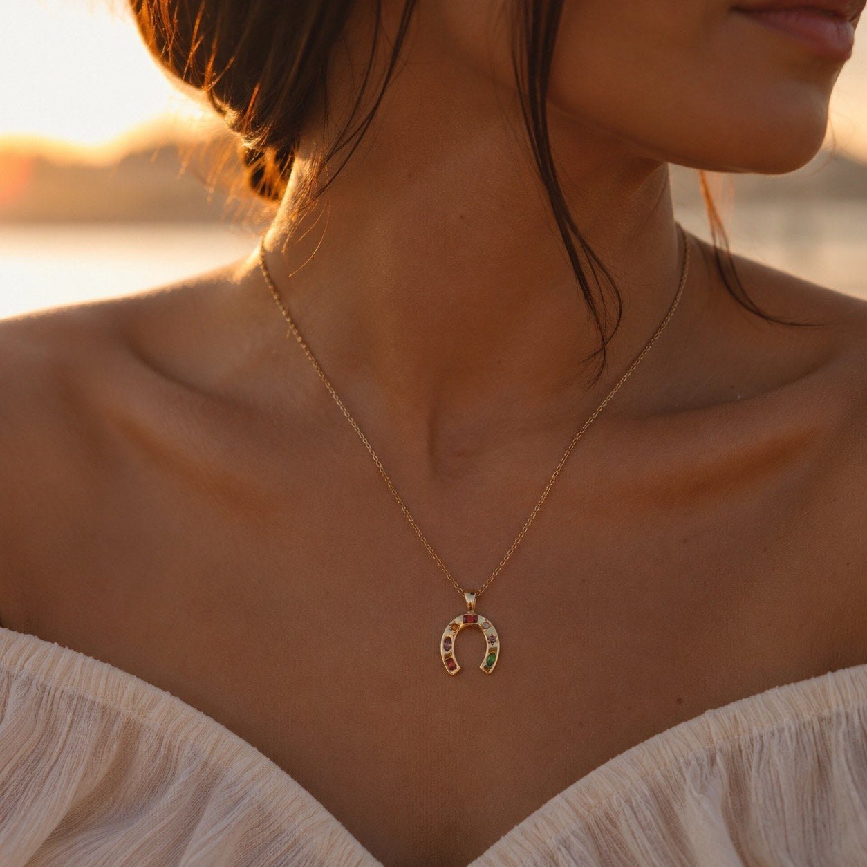 rainbow horseshoe necklace with colorful stones set in a gold horseshoe pendant