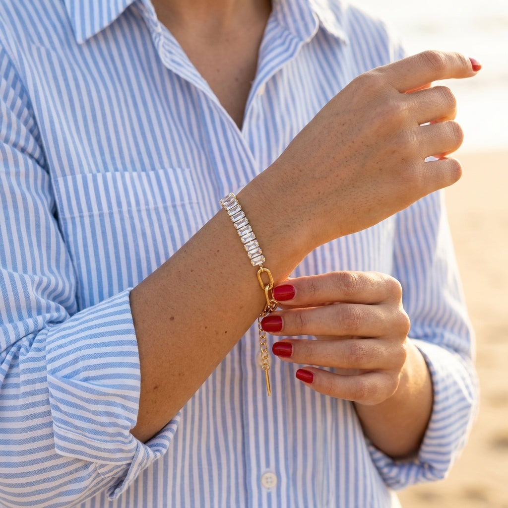 rectangular crystal tennis bracelet featuring a continuous row of clear baguette shaped stones combined with elegant gold chain detailing