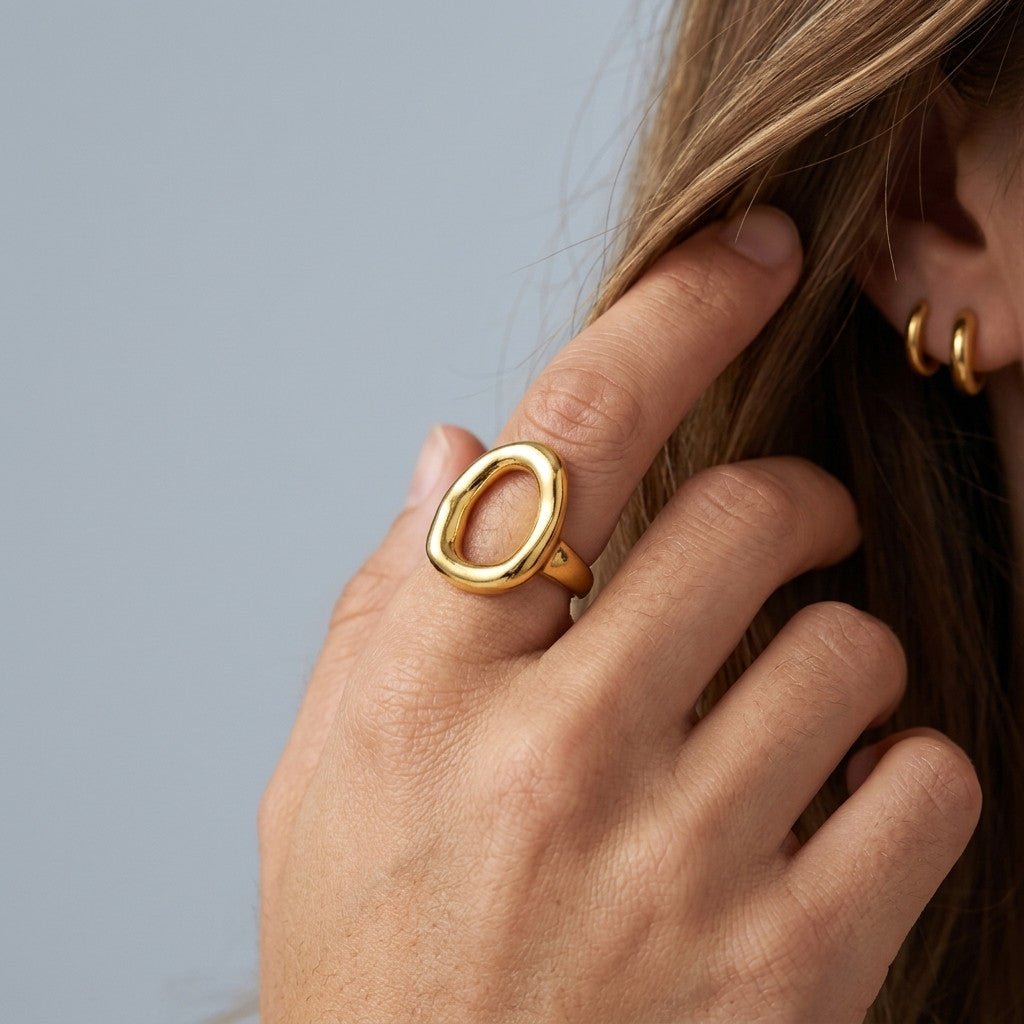 sculptural gold ring with an open oval design and smooth polished finish, worn on hand