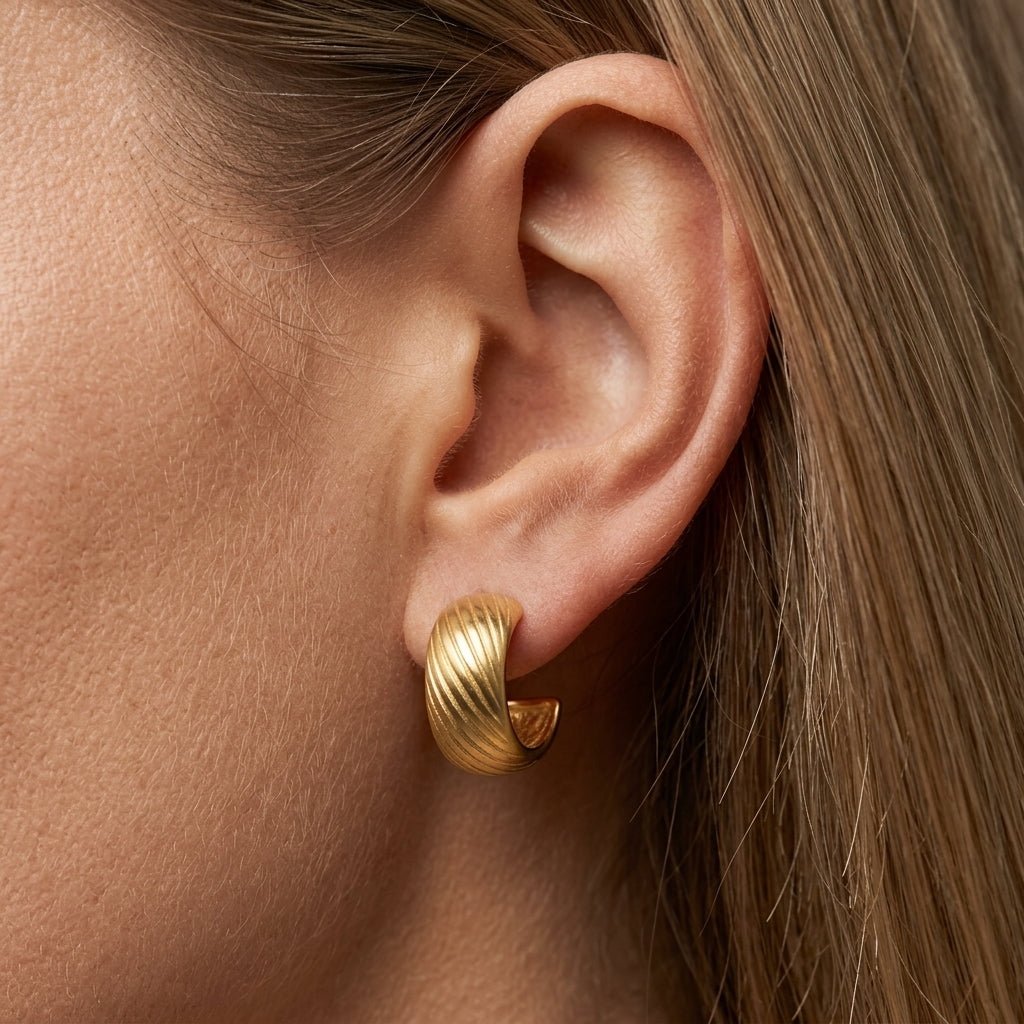 textured chunky gold hoop earrings worn on ear, ribbed matte gold huggie hoops with bold curved design, contemporary statement earrings styled for a sleek modern look