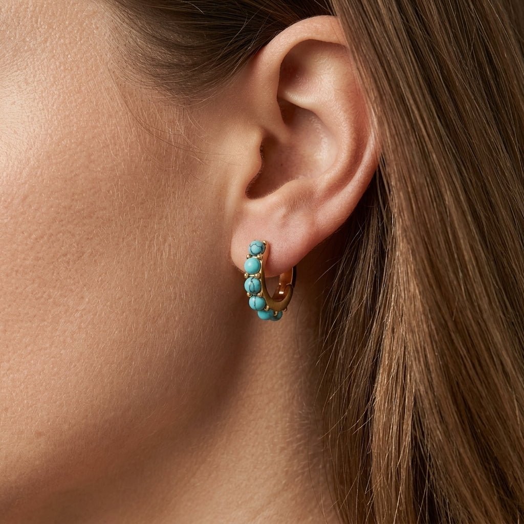 turquoise earrings, gold huggie hoop earrings worn on ear with turquoise stone bead detailing, boho inspired statement jewelry with a colorful coastal aesthetic