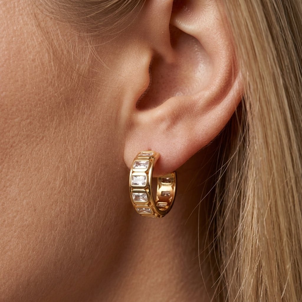 zirconia hoop earrings, gold huggie hoops worn on ear with sparkling rectangular crystal stones, elegant statement jewelry with a sleek contemporary look