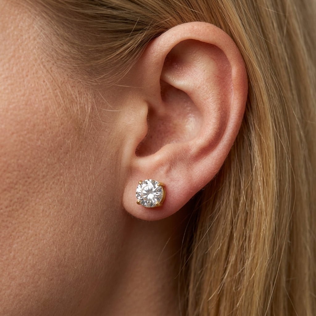 zirconia stud earrings round cut crystal solitaire stud earrings in gold setting worn on ear close up minimalist jewelry style