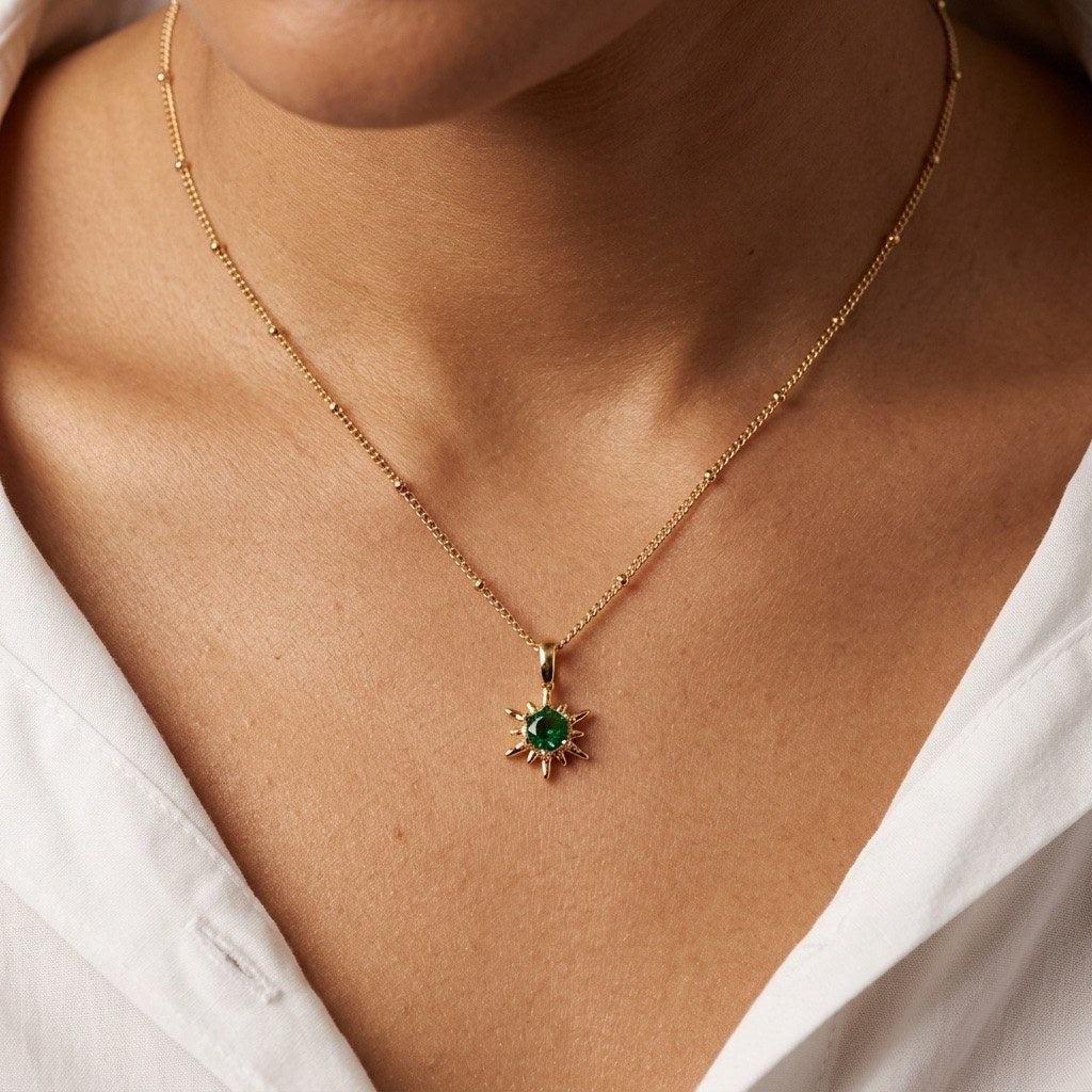 celestial green star necklace with a sparkling green center stone and delicate gold-tone sunburst details