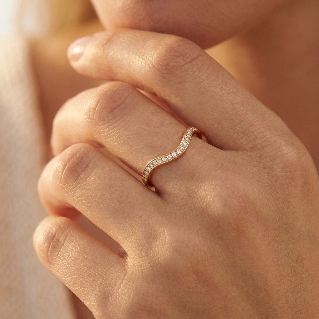 curved gold band ring with sparkling clear stones and an elegant contoured design, worn on hand