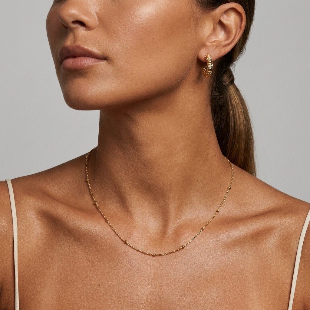 dainty gold bead necklace with small polished beads spaced along a delicate everyday chain