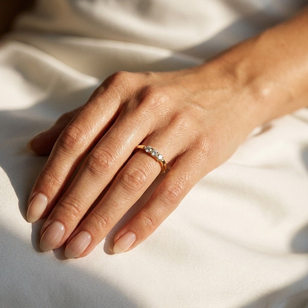 delicate gold ring with three sparkling round stones and a slim polished band