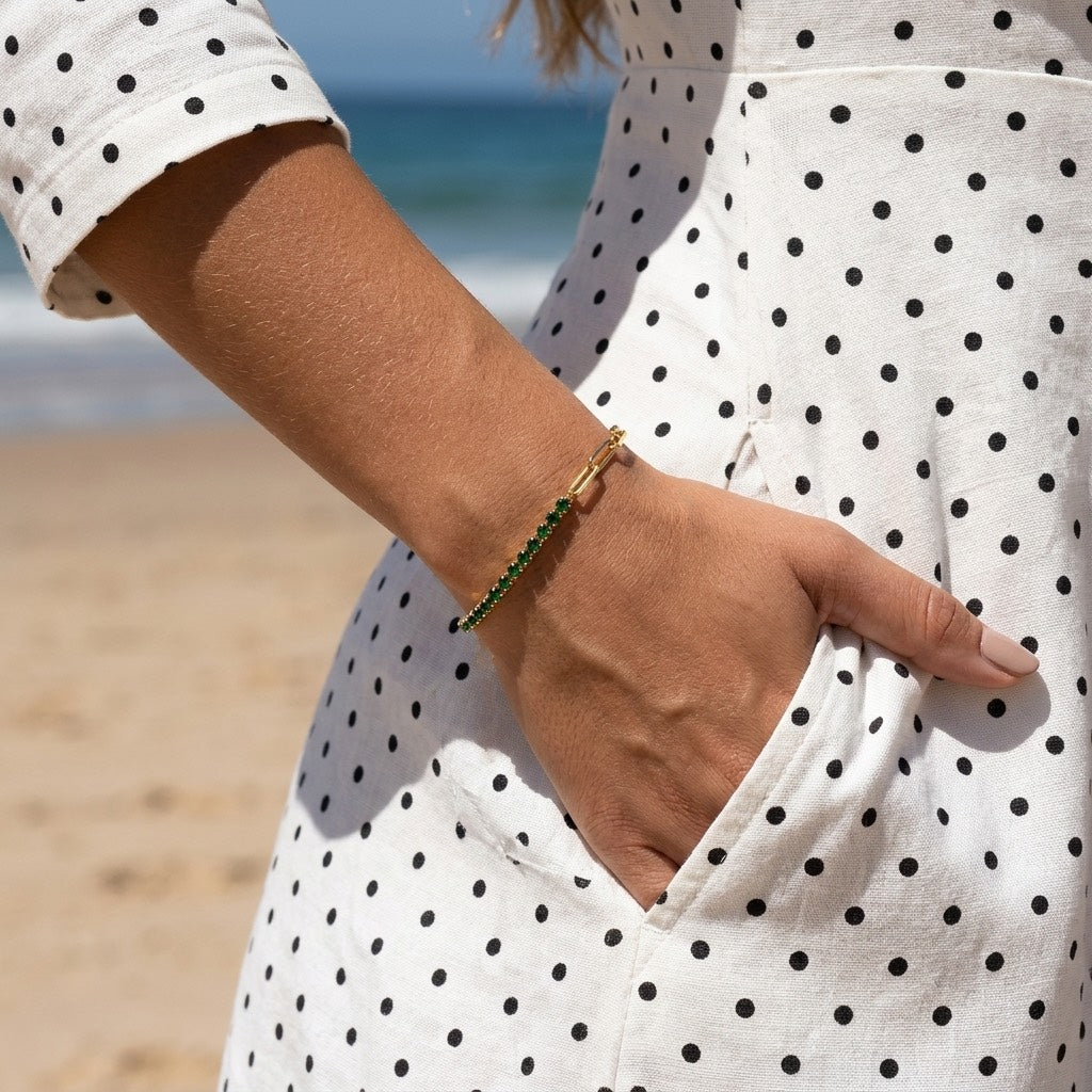 emerald green tennis bracelet featuring sparkling deep green crystals in gold prong settings paired with elongated gold links for sophisticated everyday styling 