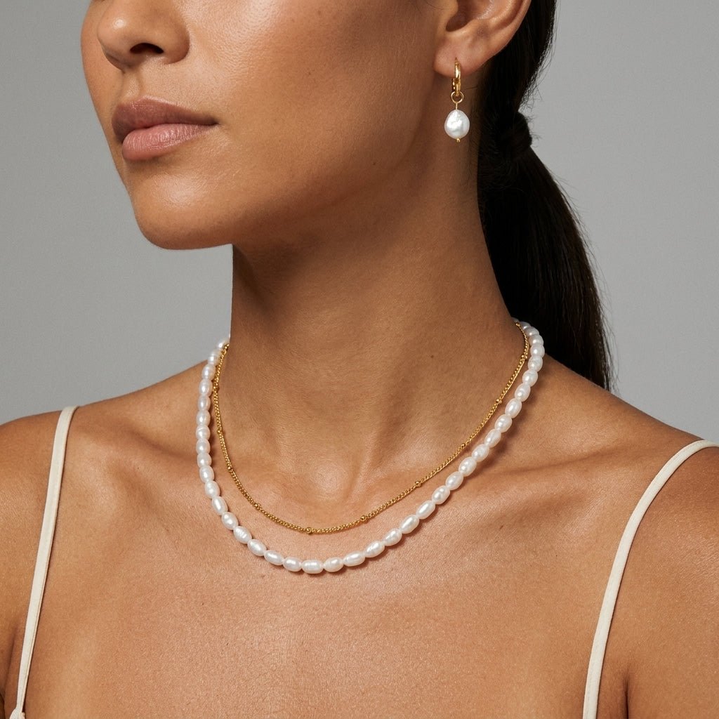 delicate gold chain layered with a classic white pearl necklace