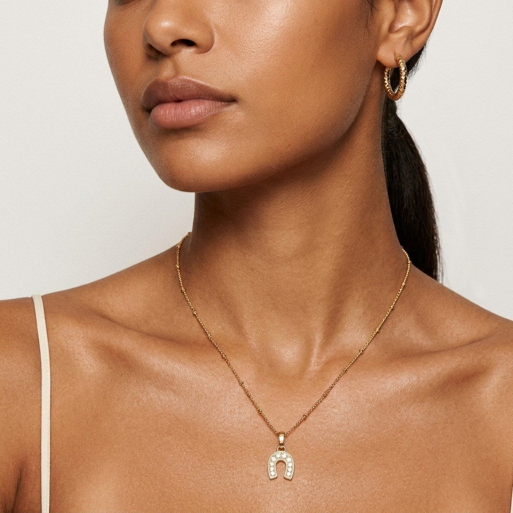 gold horseshoe necklace with a sparkling cubic zirconia pendant in a classic lucky charm design