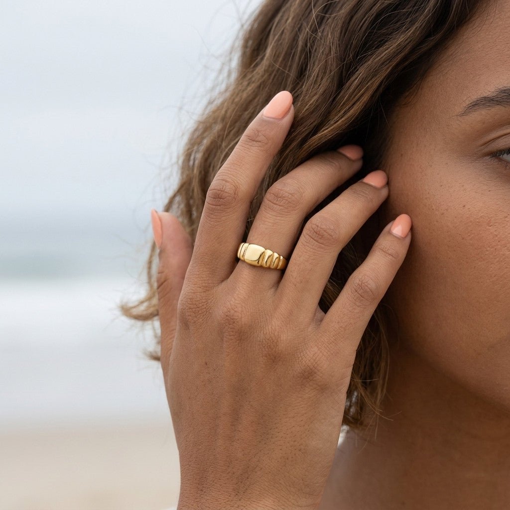 gold signet ring with a smooth polished center and bold ribbed detailing