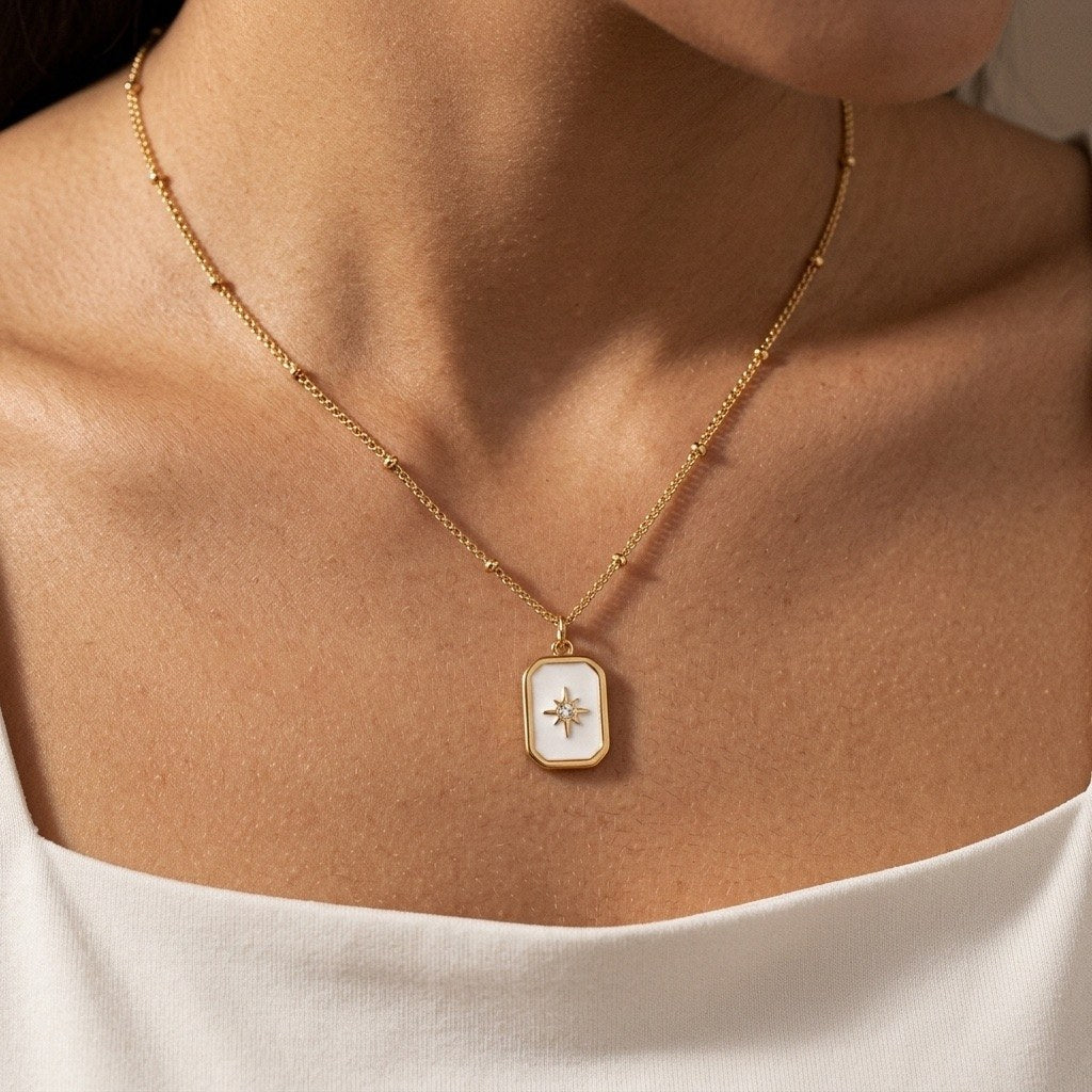 gold starburst necklace with a radiant star detail set on a white rectangular pendant