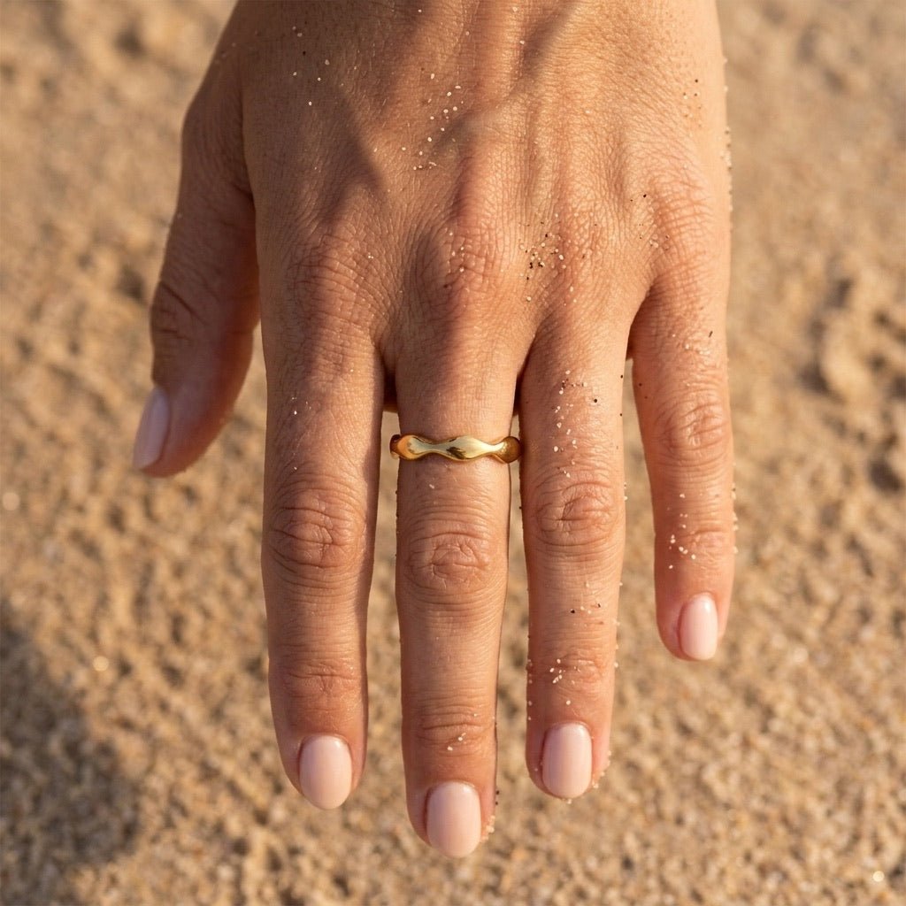 gold wave band worn on hand with a smooth polished finish and sculpted curved design