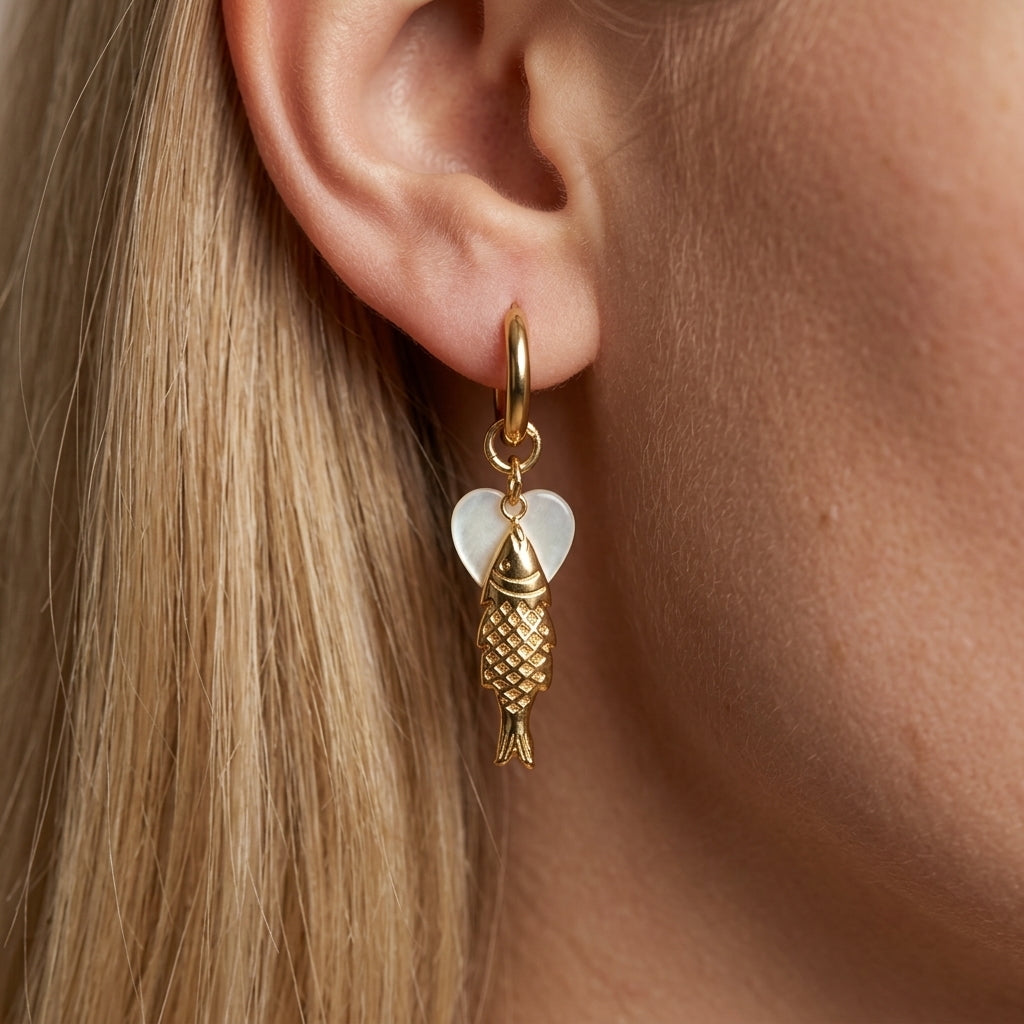 golden fish earrings playful gold fish drop earrings with a textured charm and soft white heart accent on a delicate mini hoop