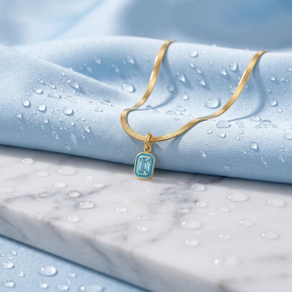 minimalist turquoise necklace featuring a delicate rectangular blue crystal pendant suspended from a smooth gold herringbone chain