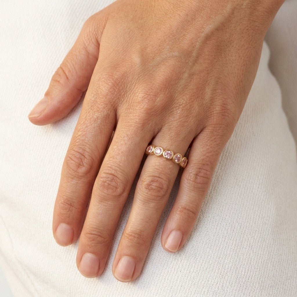 pink CZ ring with round bezel set stones on a gold band