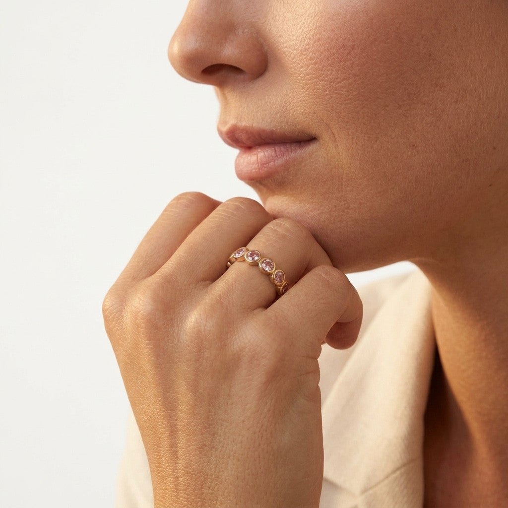 pink gemstone ring with bezel set round stones on a gold band