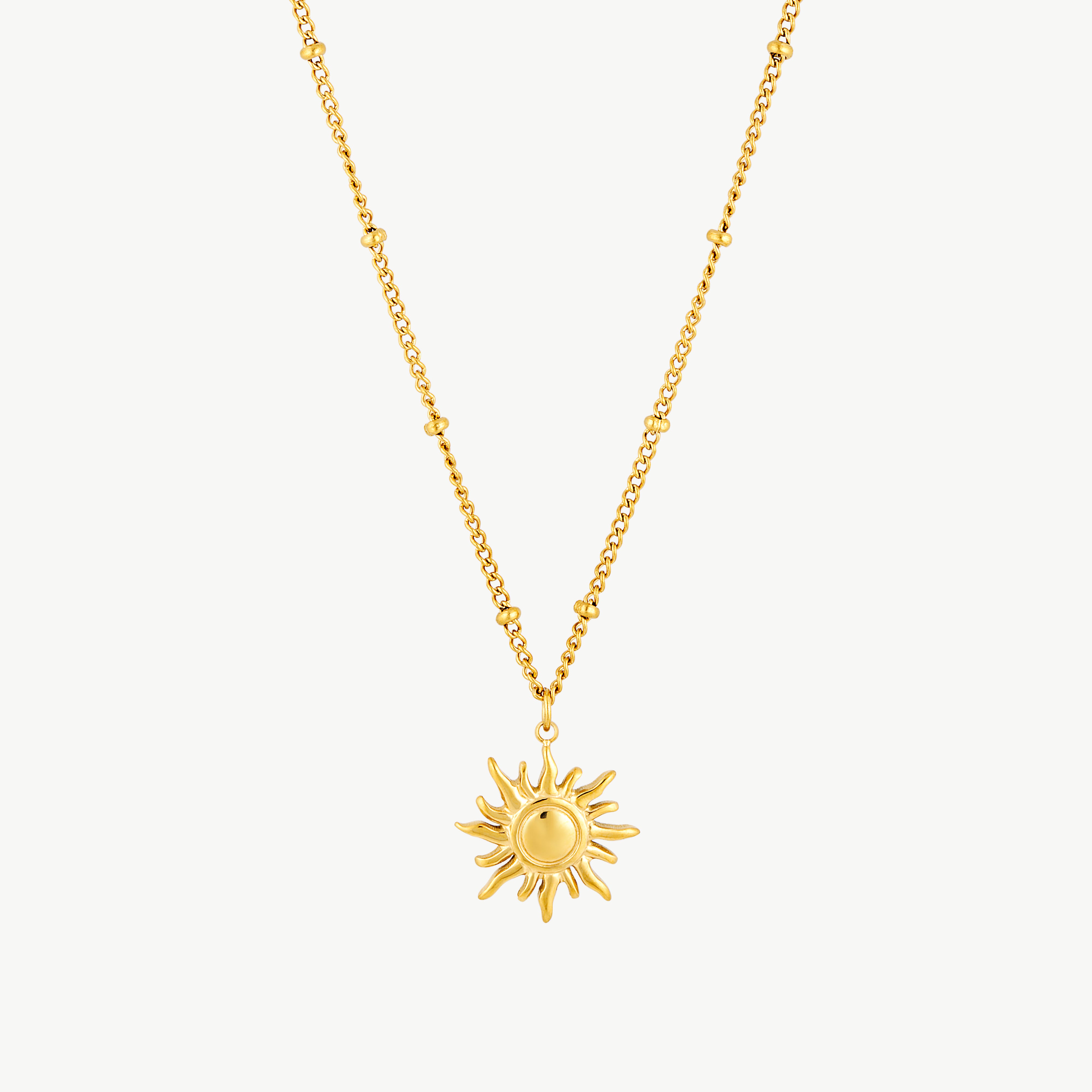 sun charm necklace with sculptural gold sun pendant and radiant rays suspended from a delicate beaded gold chain