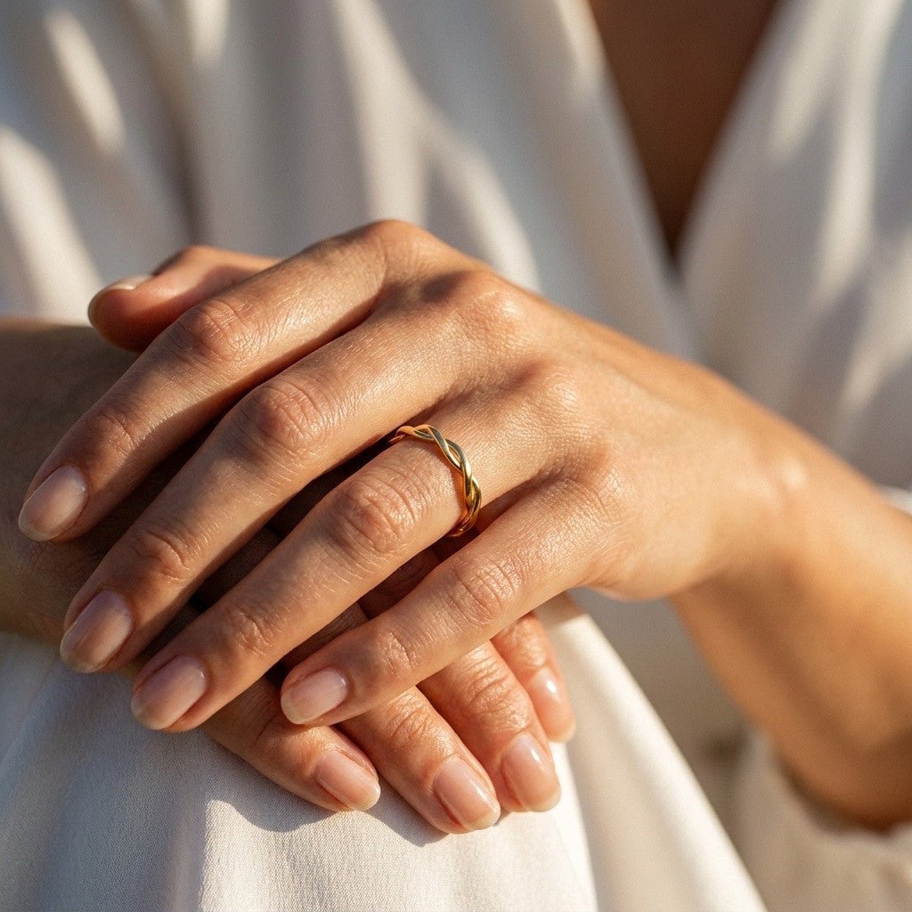 twisted gold band ring with a polished intertwined design and slim sculpted profile, worn on hand