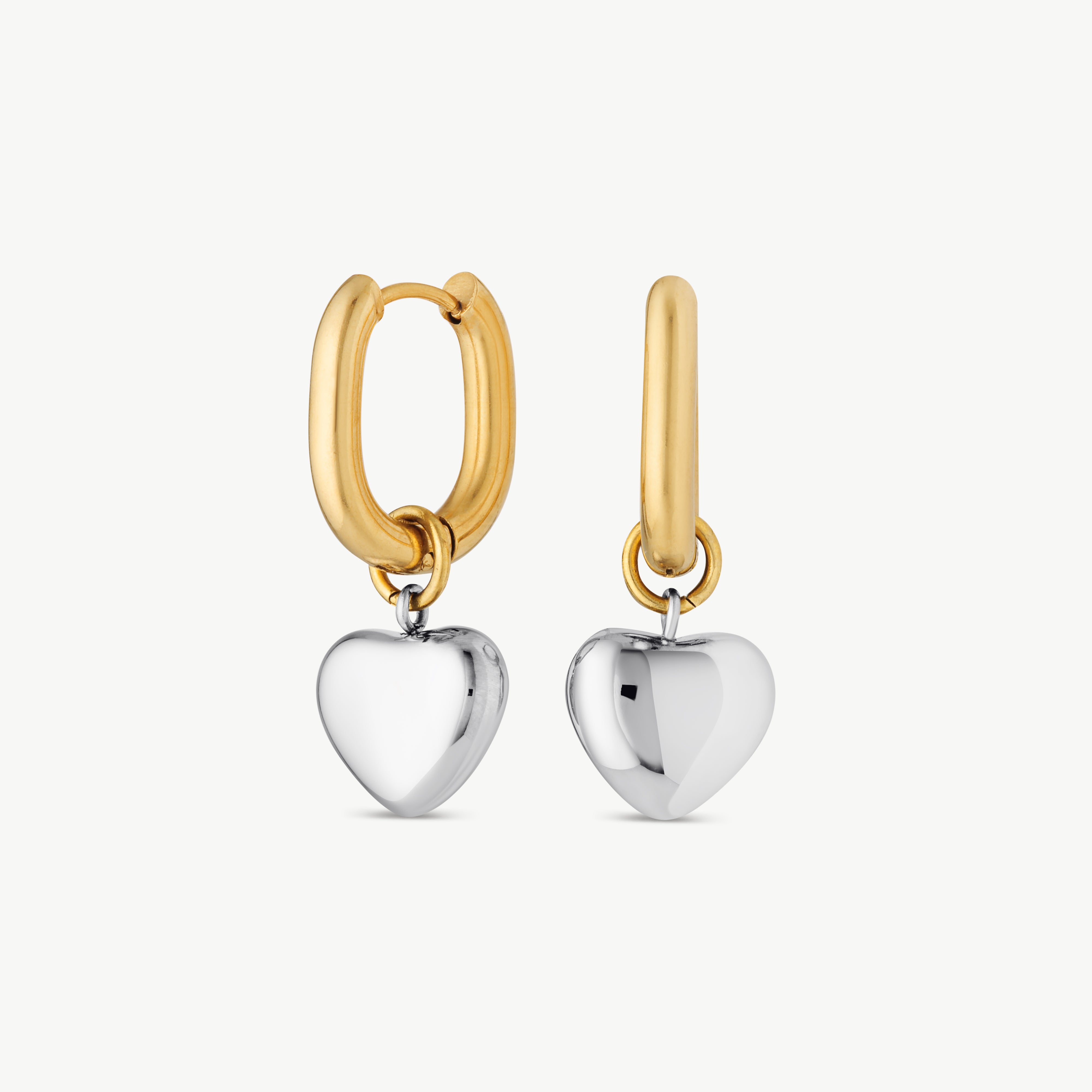 two tone heart earrings with polished gold hoops and sculptural silver heart charms in an elegant mixed metal design