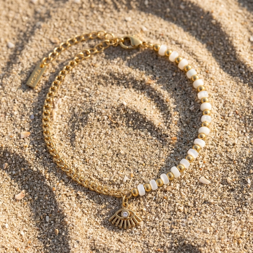 white bead evil eye bracelet for women featuring small white beads alternating with polished gold beads and a dangling gold evil eye charm 